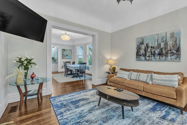 living room featuring wood finished floors, visible vents, and baseboards