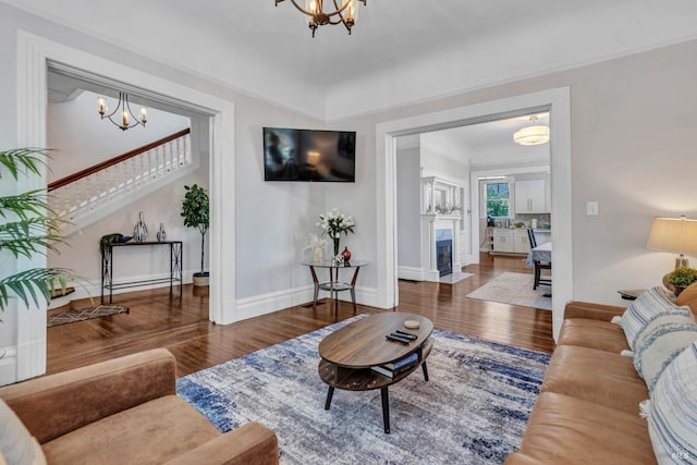 living area with a fireplace, a notable chandelier, baseboards, and wood finished floors