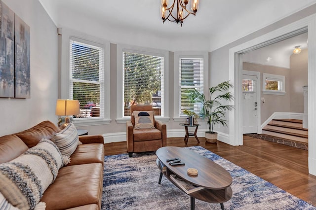 living area with a notable chandelier, plenty of natural light, baseboards, and wood finished floors