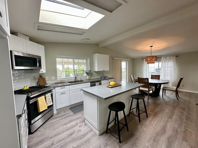 kitchen featuring appliances with stainless steel finishes, a kitchen breakfast bar, a healthy amount of sunlight, and a sink