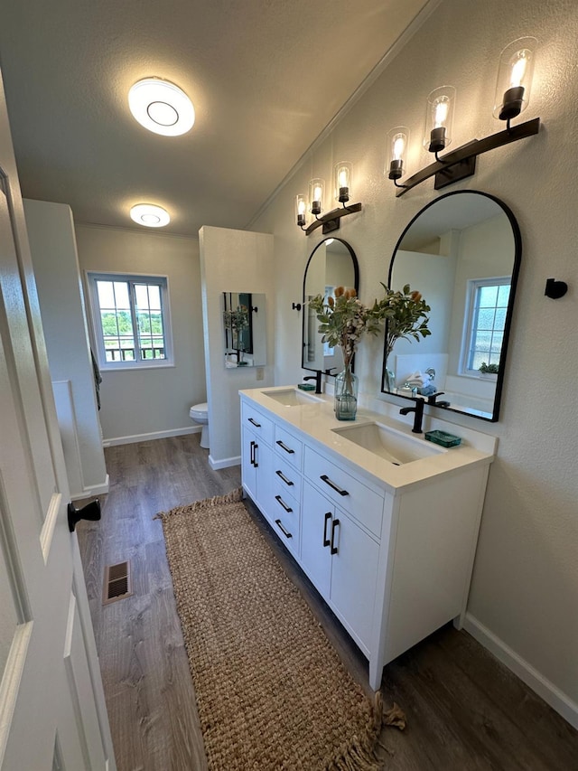bathroom featuring toilet, visible vents, a sink, and wood finished floors