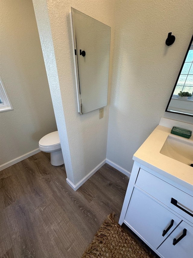 bathroom with vanity, toilet, baseboards, and wood finished floors
