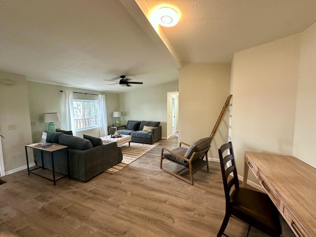 living room featuring a ceiling fan, baseboards, and wood finished floors