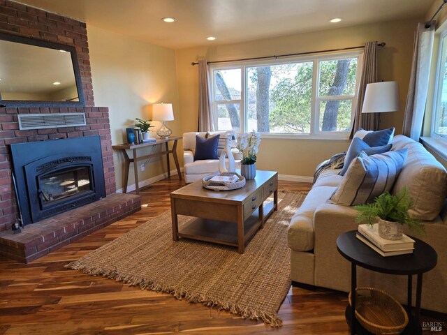 living room with a brick fireplace and dark hardwood / wood-style floors