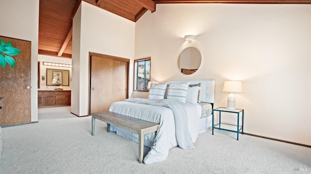 carpeted bedroom featuring wooden ceiling, high vaulted ceiling, ensuite bath, beam ceiling, and a closet