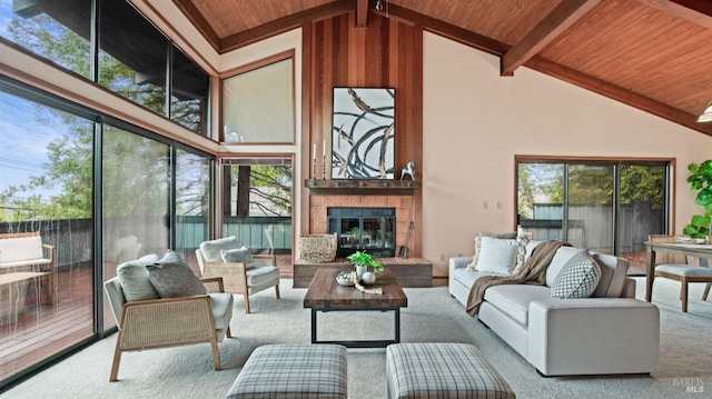 living room featuring a tile fireplace, beam ceiling, light carpet, and wood ceiling