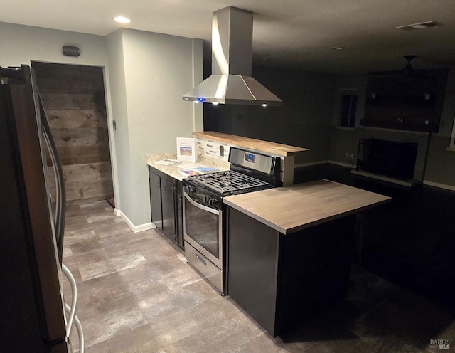 kitchen featuring a fireplace, stainless steel appliances, light countertops, a peninsula, and extractor fan