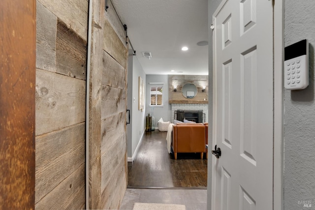 hallway with recessed lighting, wood finished floors, baseboards, and a barn door