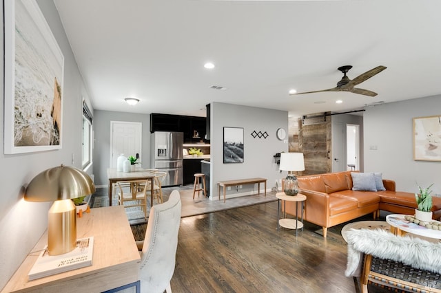 living room with ceiling fan, a barn door, recessed lighting, visible vents, and dark wood-style floors