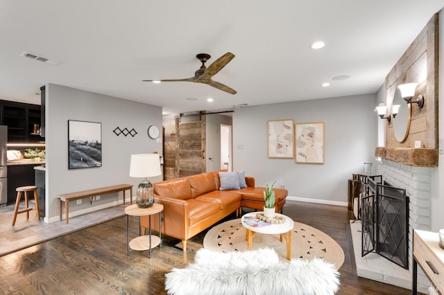 living room with dark wood finished floors, recessed lighting, visible vents, a barn door, and a ceiling fan