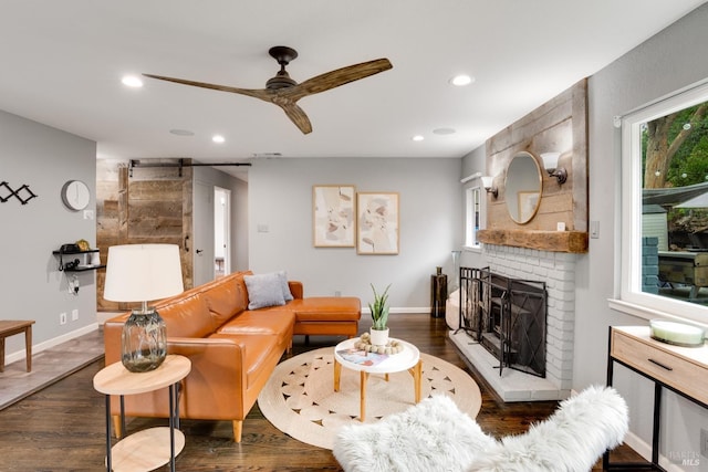 living room with dark wood-style flooring, recessed lighting, a barn door, a brick fireplace, and ceiling fan