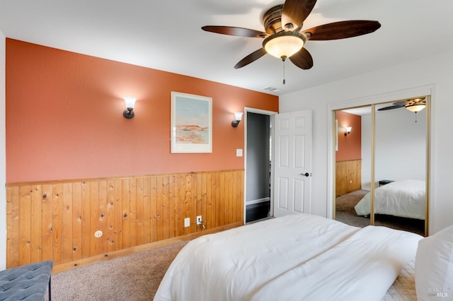 bedroom with wainscoting, wooden walls, and light colored carpet