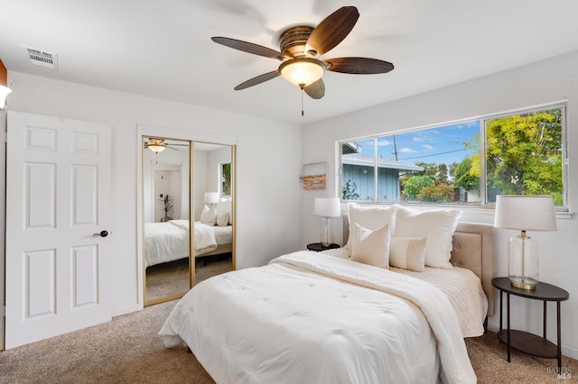 carpeted bedroom with a closet, visible vents, and a ceiling fan