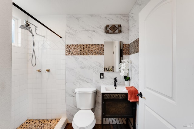 full bathroom with vanity, a shower stall, toilet, and tile walls