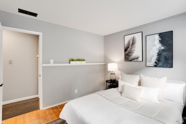 bedroom with visible vents, baseboards, and wood finished floors