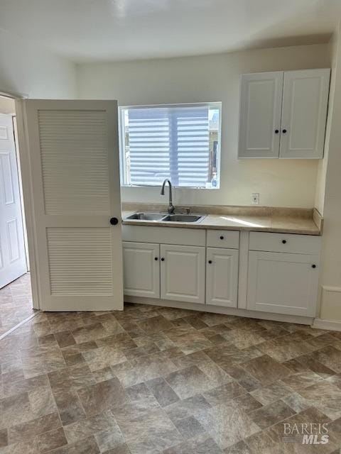 kitchen with white cabinets, sink, and light tile floors