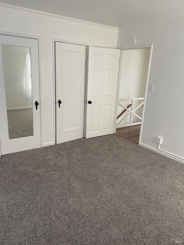 unfurnished bedroom featuring dark carpet, a closet, and crown molding