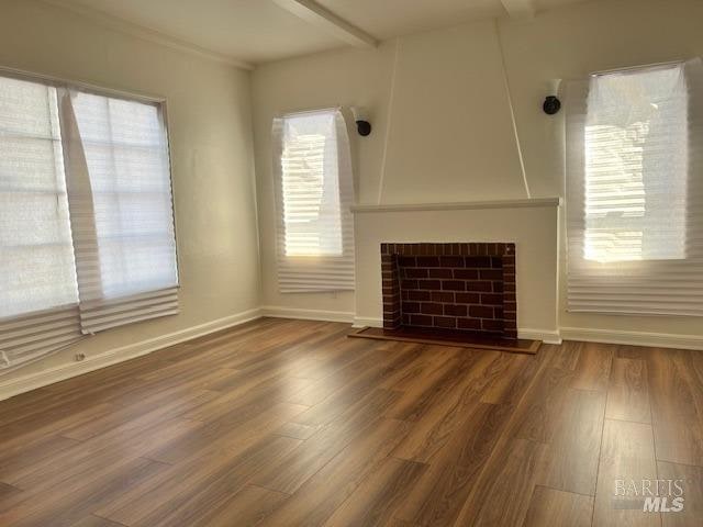 unfurnished living room with a healthy amount of sunlight, dark wood-type flooring, and a fireplace