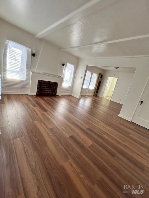 unfurnished living room with beam ceiling and dark wood-type flooring