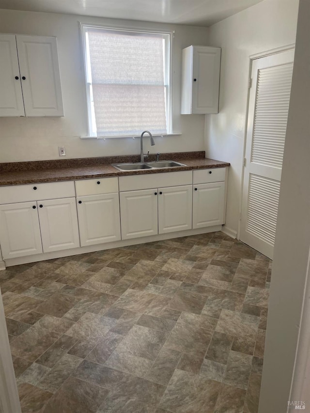 kitchen featuring sink, white cabinets, and dark tile floors