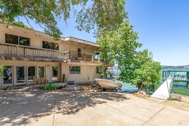 rear view of house featuring french doors, a water view, and a balcony