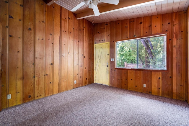 unfurnished room featuring beam ceiling, a ceiling fan, wood ceiling, light carpet, and wood walls