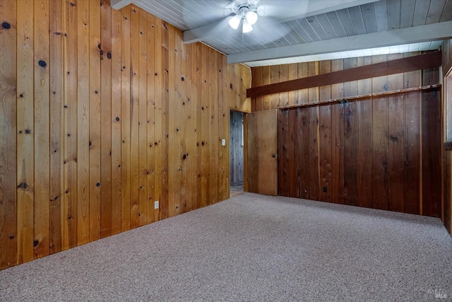 spare room with lofted ceiling with beams, carpet, a ceiling fan, and wooden walls