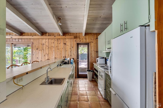 kitchen with wooden walls, white appliances, a sink, light countertops, and beam ceiling