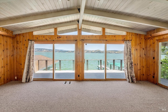 interior space with vaulted ceiling with beams, visible vents, a water and mountain view, carpet flooring, and wood walls