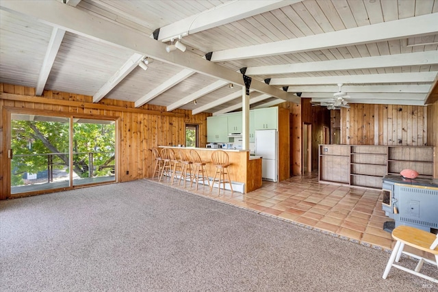 interior space featuring lofted ceiling with beams, track lighting, wood walls, and light colored carpet