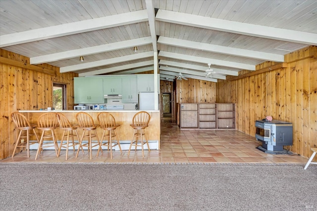 interior space featuring carpet, a wood stove, wooden walls, a peninsula, and fridge