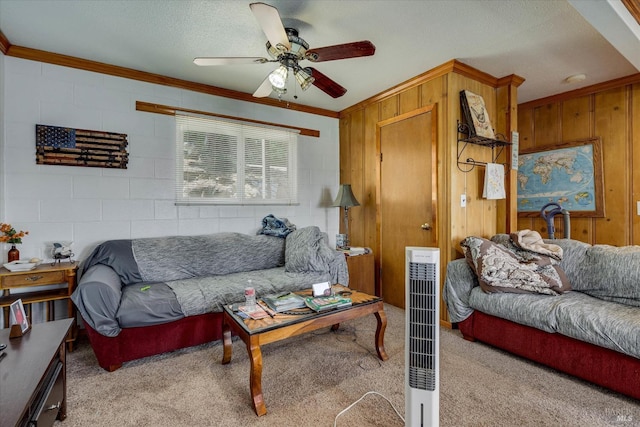 living area featuring light carpet, concrete block wall, a ceiling fan, ornamental molding, and a textured ceiling