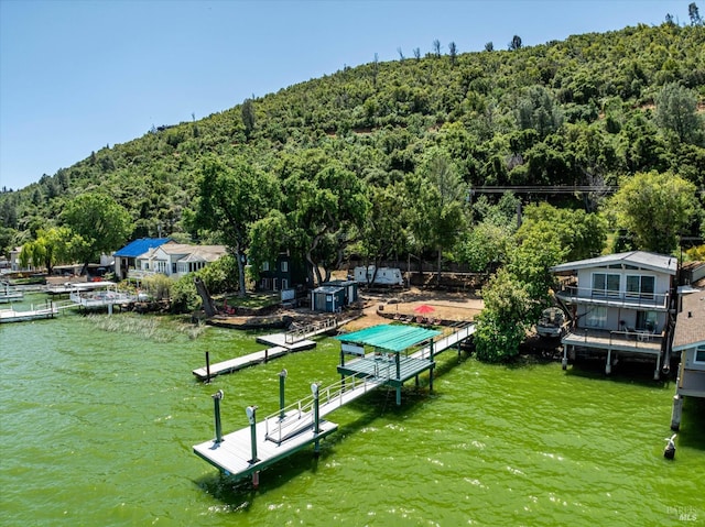 view of property's community with a dock, a water view, and a wooded view