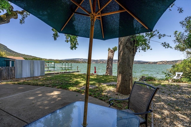 view of patio with a water view and fence