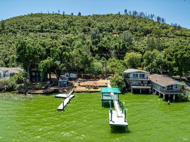 birds eye view of property with a water view and a wooded view