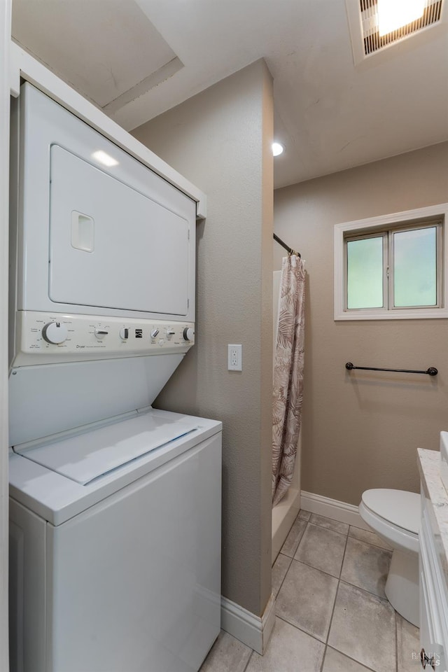 laundry area with stacked washing maching and dryer and light tile patterned floors