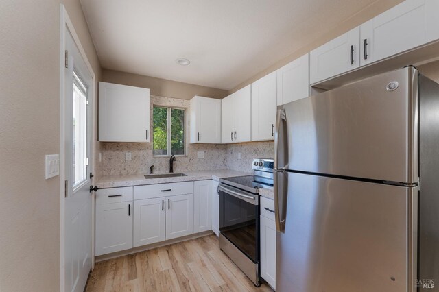 kitchen with sink, white cabinets, stainless steel electric range oven, and tasteful backsplash