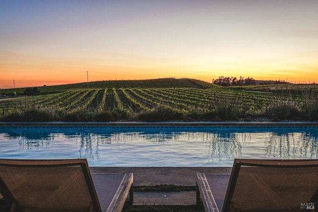 pool at dusk featuring a rural view