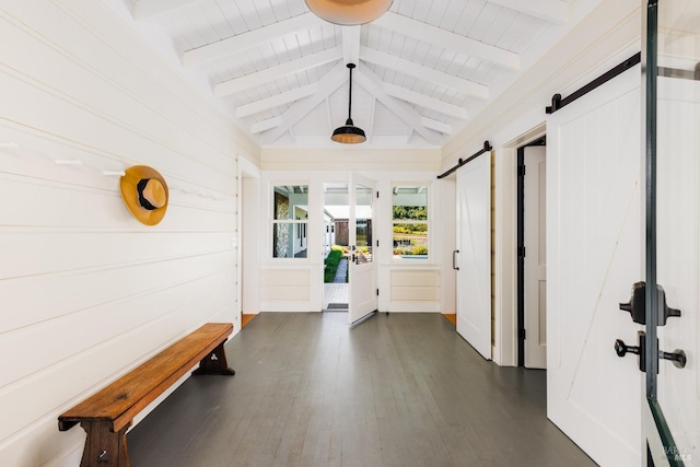 hallway featuring dark wood-type flooring, vaulted ceiling with beams, and a barn door