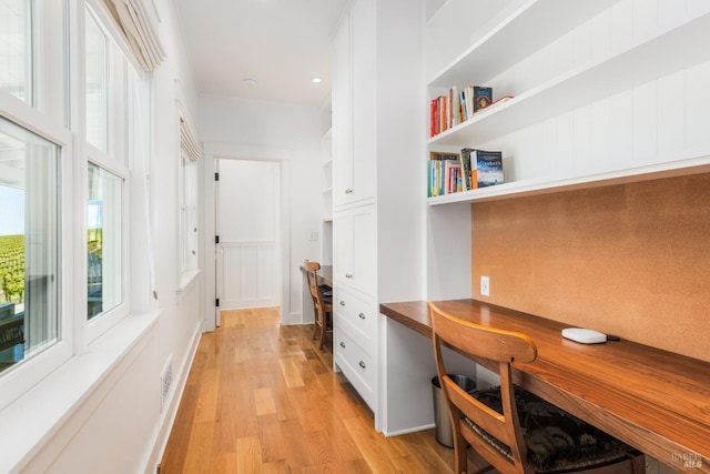 home office featuring built in desk and light hardwood / wood-style floors