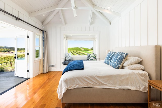 bedroom featuring access to outside, vaulted ceiling with beams, wood-type flooring, and multiple windows