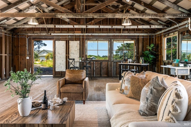 living room featuring wooden walls, wood-type flooring, and vaulted ceiling with beams