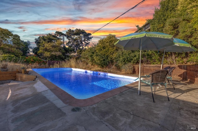 pool at dusk featuring a patio area