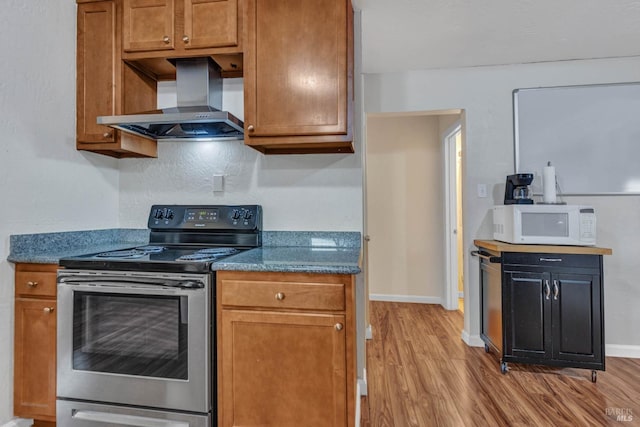 kitchen featuring stainless steel electric range oven, light wood-type flooring, and wall chimney exhaust hood