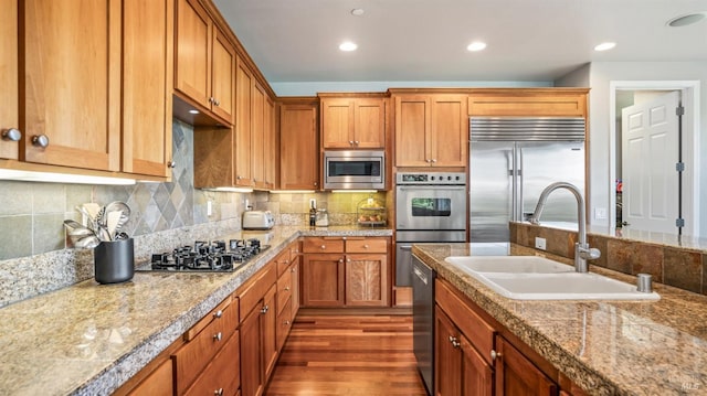 kitchen featuring built in appliances, backsplash, dark hardwood / wood-style flooring, and sink