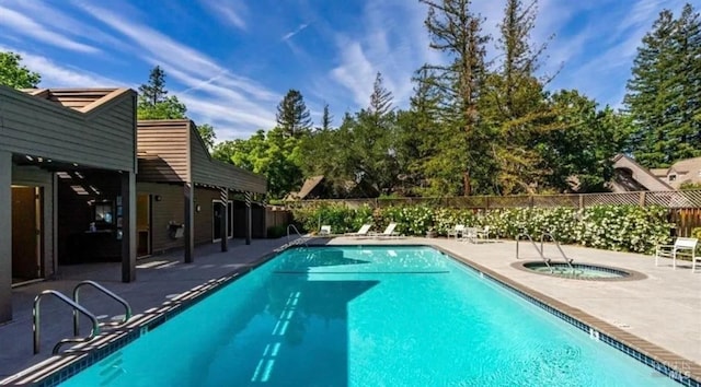 pool featuring a hot tub, a patio, and fence