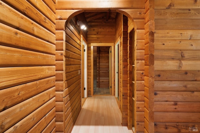 hallway featuring light wood-type flooring and rustic walls