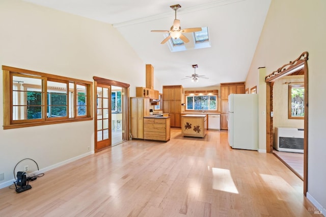 unfurnished living room featuring a skylight, light hardwood / wood-style flooring, high vaulted ceiling, and heating unit