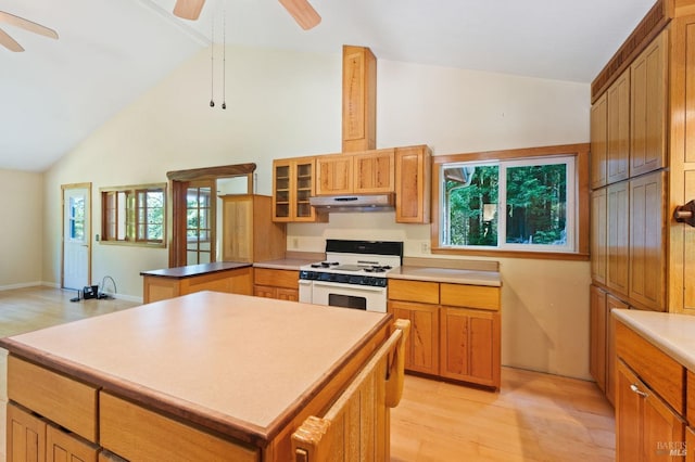 kitchen with white stove, light hardwood / wood-style flooring, a kitchen island, and ceiling fan