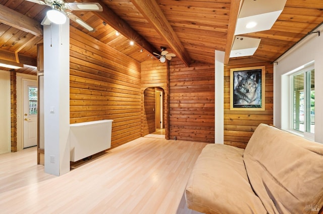 unfurnished room featuring vaulted ceiling with beams, light wood-type flooring, a wealth of natural light, and wooden ceiling